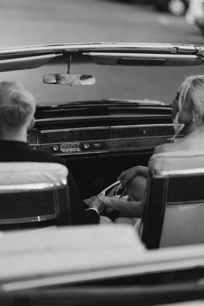 Couple seated in the front seat of the full-size convertible 'Donald,' holding hands